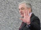 Conrad Black stands in front of granite wall with one hand up. Copyright bildungblog.blotspot.com 2010