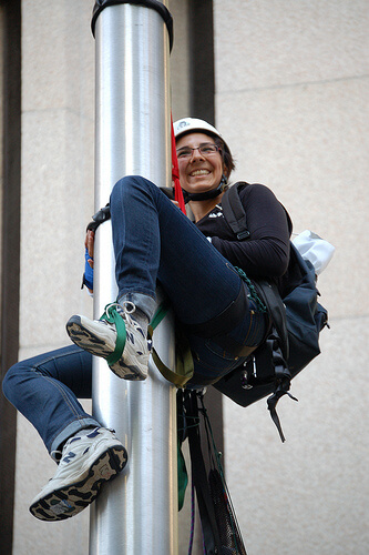 Eriel Tchekwie Deranger climbs the flagpole in front of RBC on July 28, 2009. Photos courtesy Rainforest Action Network.