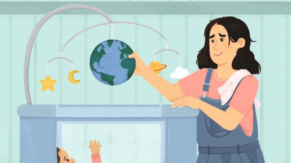 Young woman with shoulder length dark hair, blue overalls, and a pink t-shirt stands beside a crib holding the centre of a mobile designed like planet earth smiling at small child in crib wearing a pink onesie. There are animals lined up on a shelf on the wall behind them.