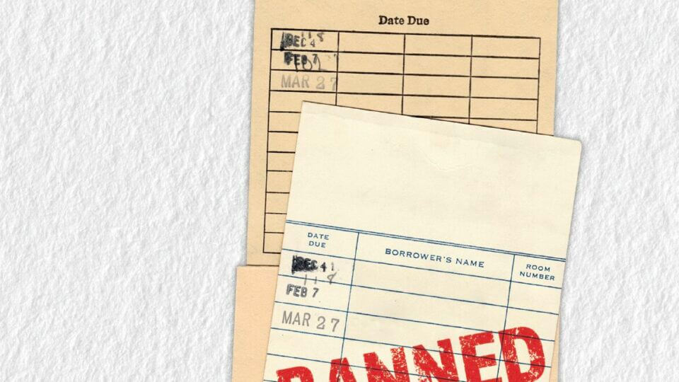 An old-fashioned library card system from the back of a library book is stamped with the word BANNED in all caps