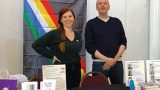 Photo of a man and a woman standing behind a display table.