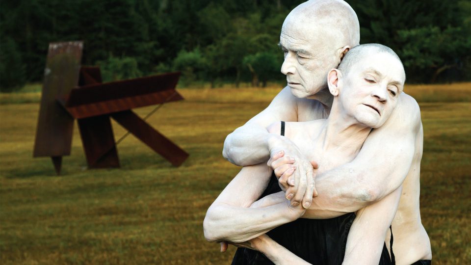 Photo of a couple who are painted white embracing.