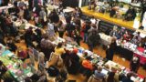 Overhead photo of a vendor hall filled with tables and people. A sign in the top right corner of the image reads 'Zine Making Zone.'