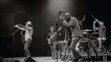Black and white photo of a band playing on a stage.