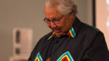 Image of an Indigenous man with grey hair speaking at an event.